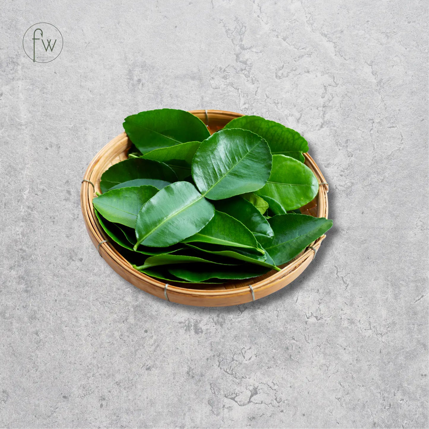 Fresh green citrus peel slices piled in a small round woven bamboo tray, set against a textured gray concrete background.