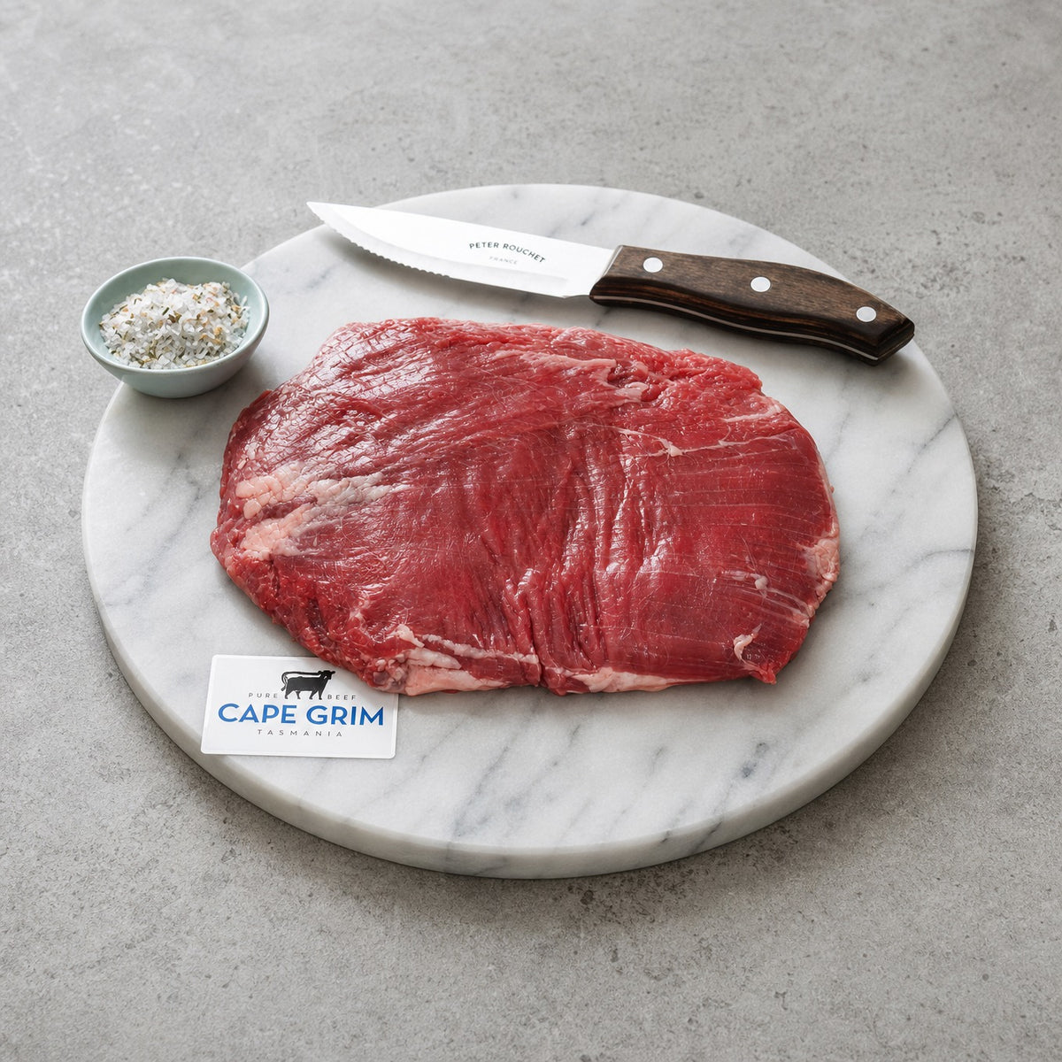 Cape Grime Lean Flank Steak on a Marble Plate with Sea salt and knife.