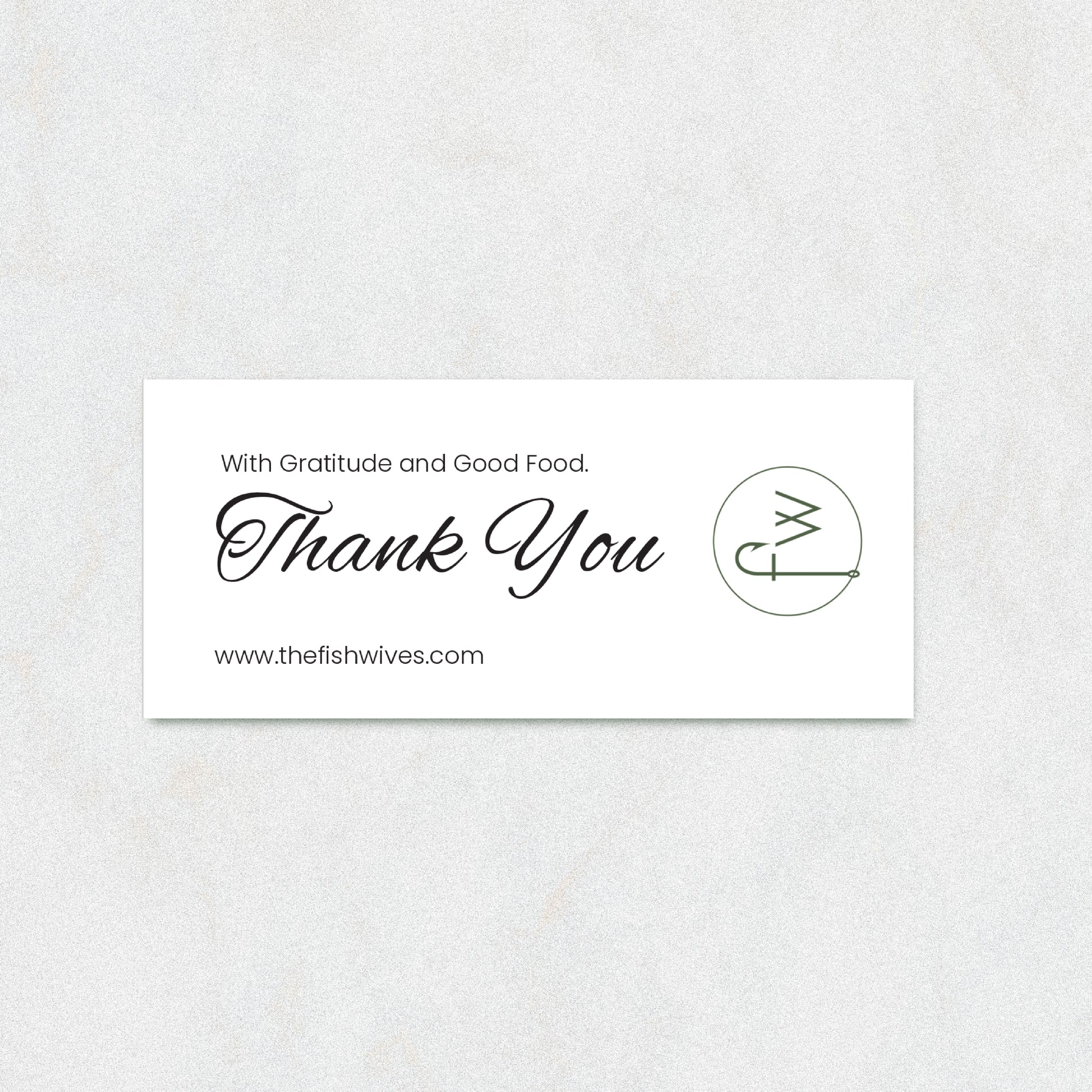 A rectangular white thank-you card with elegant black script reading 'Thank You' and smaller text 'With Gratitude and Good Food.' and 'www.