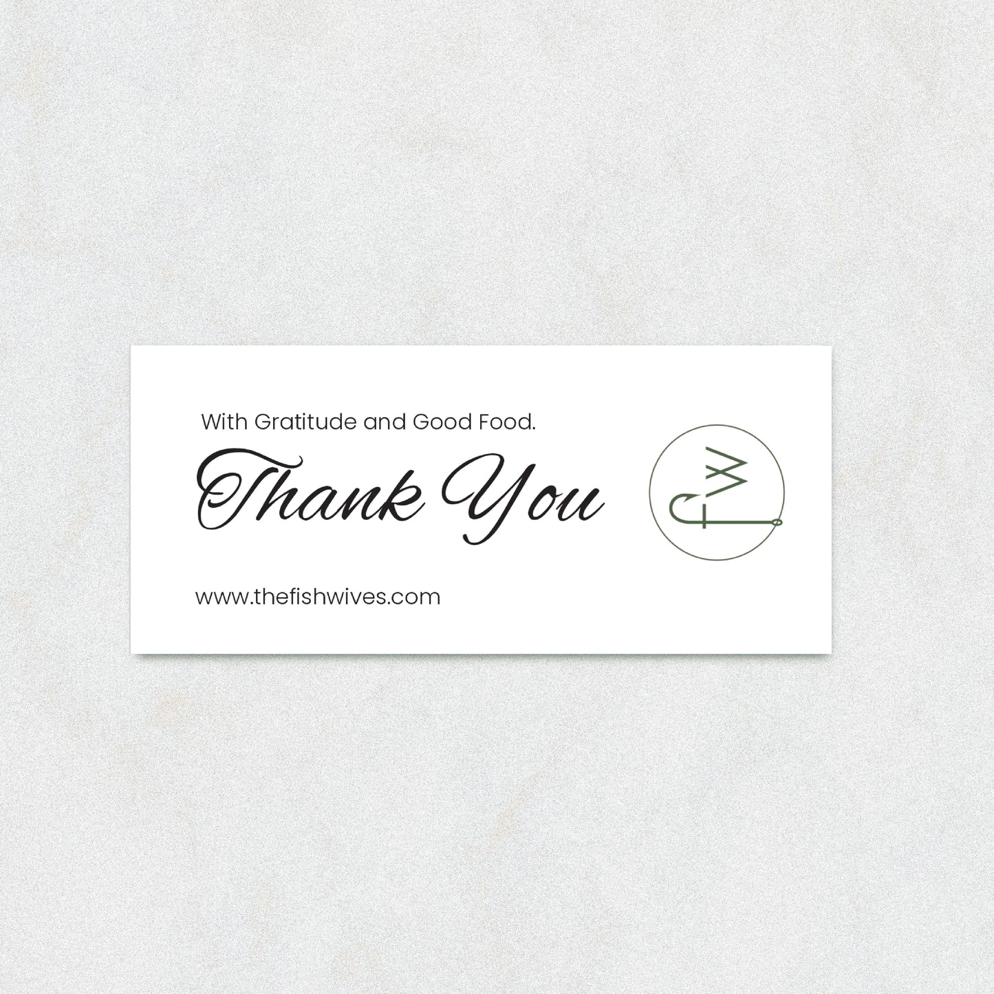 A rectangular white thank-you card with elegant black script reading 'Thank You' and smaller text 'With Gratitude and Good Food.' and 'www.