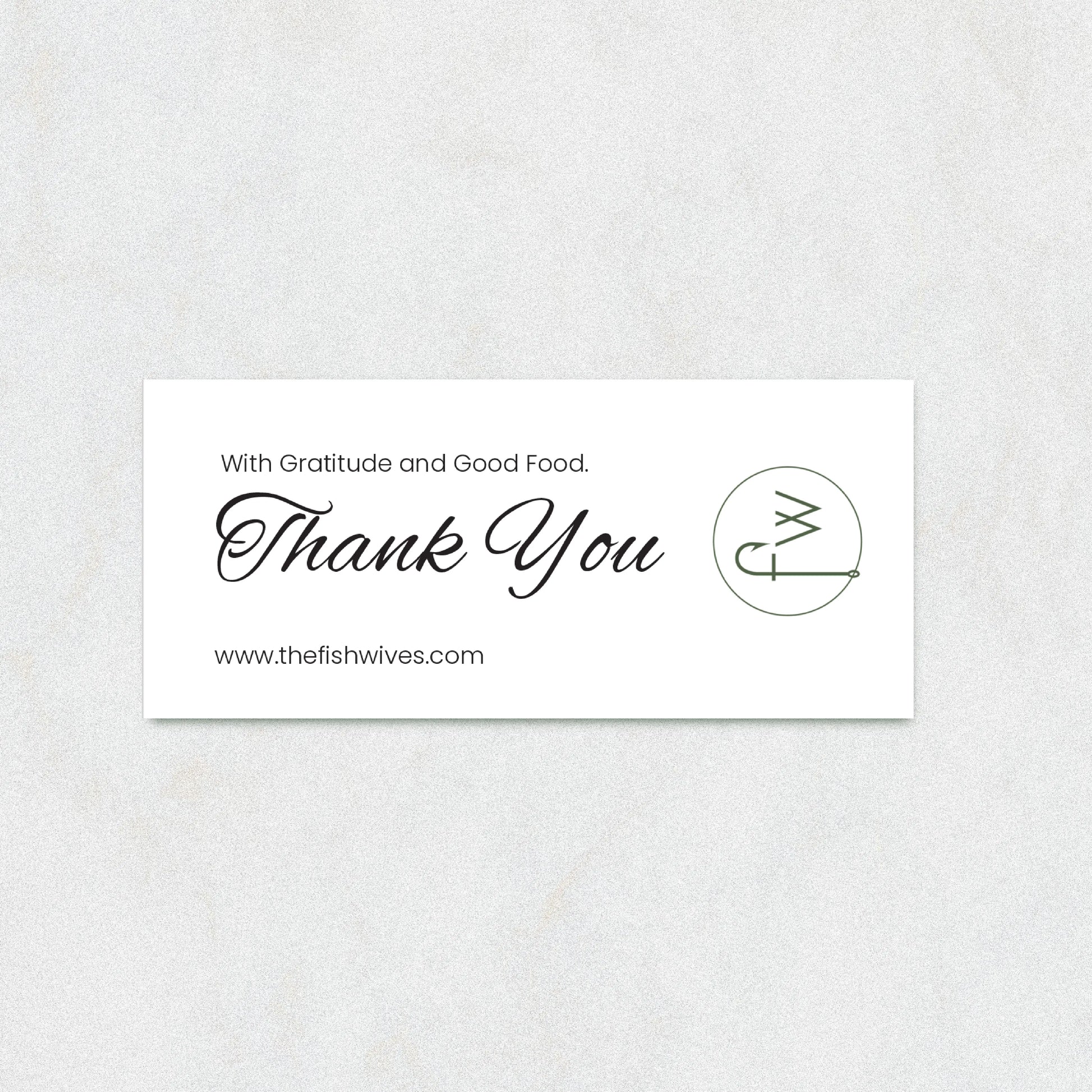 A rectangular white thank-you card with elegant black script reading 'Thank You' and smaller text 'With Gratitude and Good Food.' and 'www.