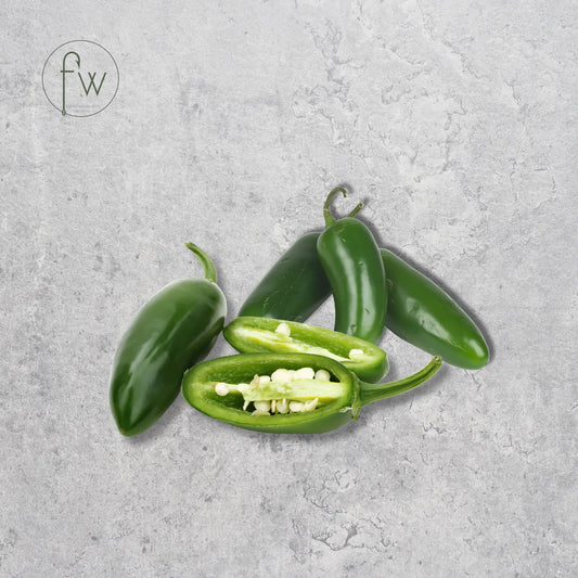 Green jalapeño peppers on a gray concrete surface with 'fw' logo.