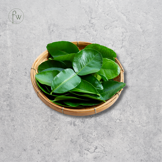 Fresh green citrus peel slices piled in a small round woven bamboo tray, set against a textured gray concrete background.