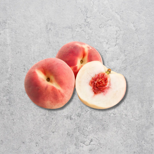 Three fresh peaches on a textured light gray background, with two whole peaches and one cut open to show the red flesh and pale skin.