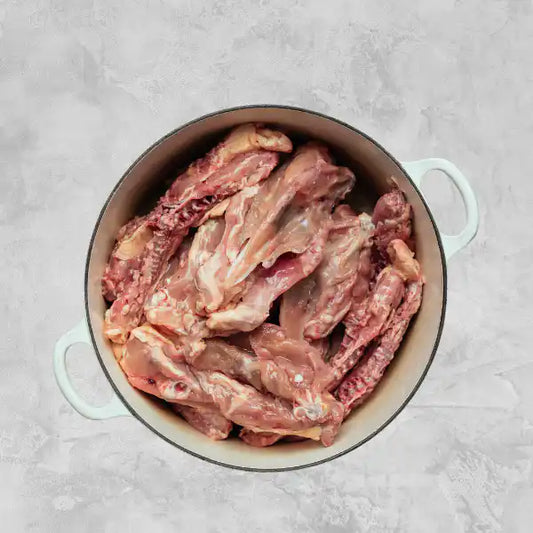 Certified organic chicken carcass, broken into pieces, on a light background.