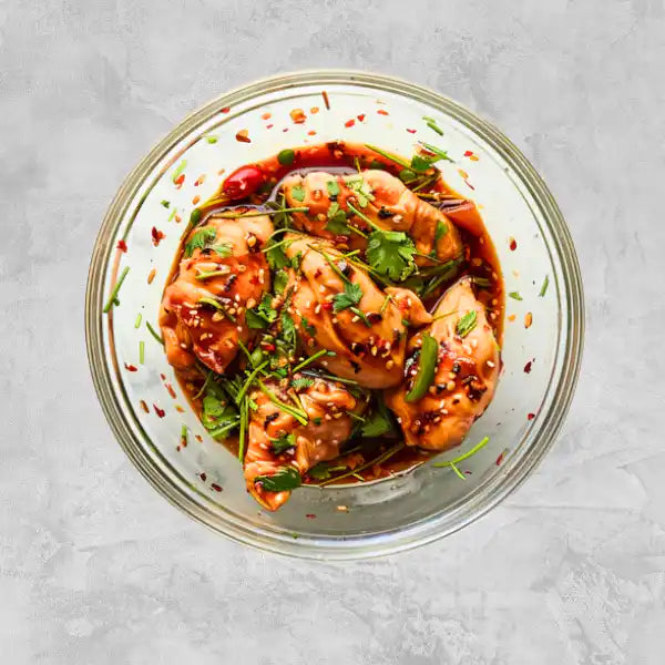 Marinated certified organic chicken breasts on a light background.
