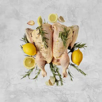 Marinated certified organic butterflied whole chicken on a light background.