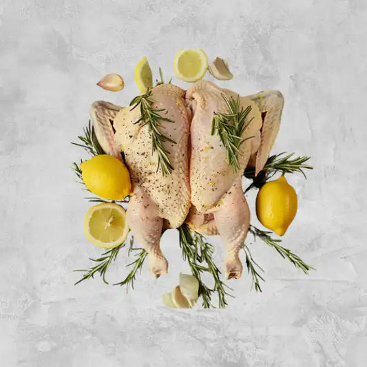 Marinated certified organic butterflied whole chicken on a light background.