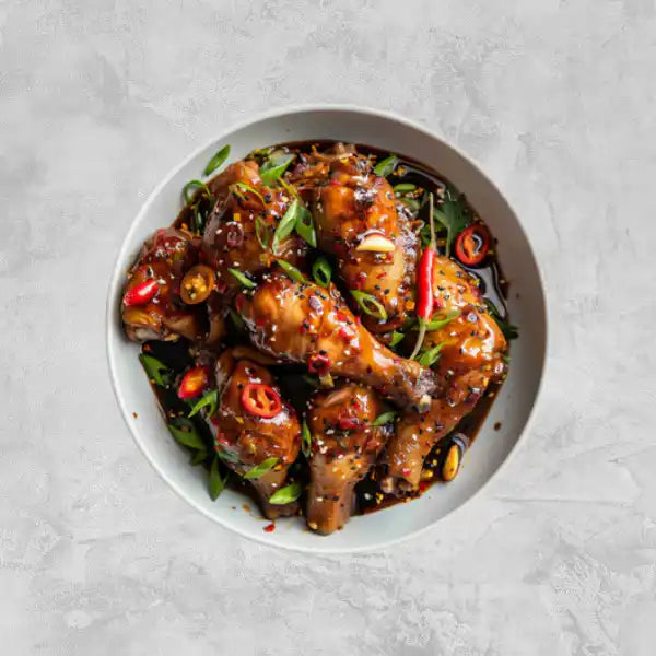Marinated certified organic chicken drumsticks on a light background.