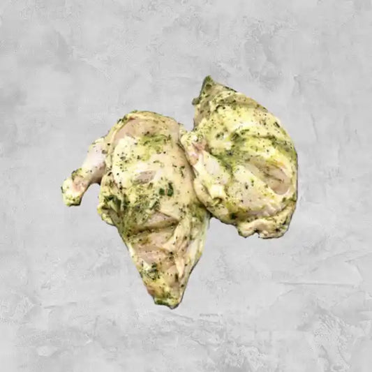 Marinated certified organic chicken breast supreme, skin on, on a light background.