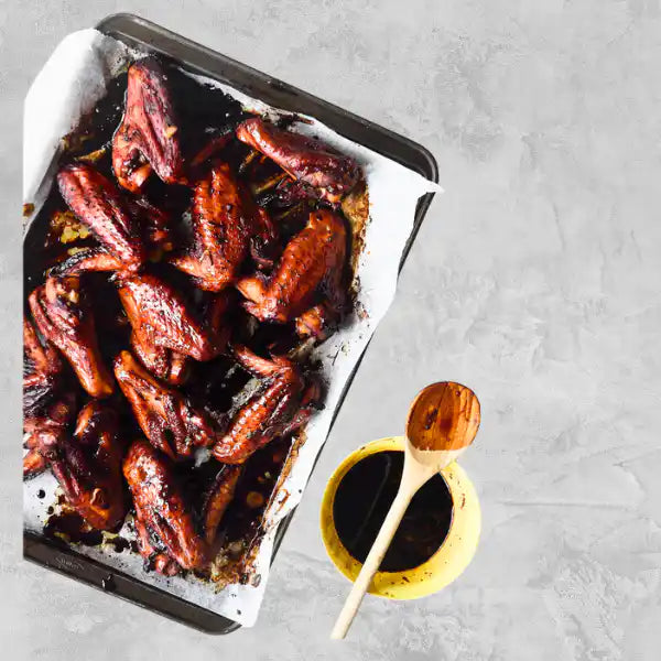 Marinated certified organic chicken wings on a light background.