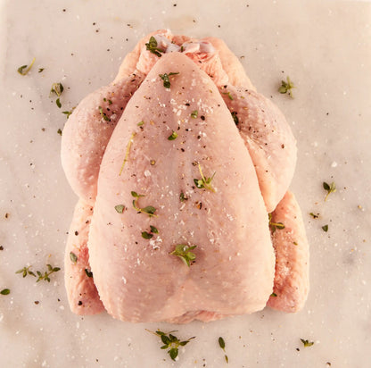 Whole certified organic chicken on a chopping board.